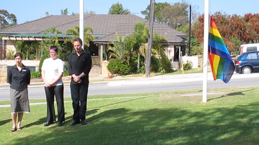 Three people standing by a flag