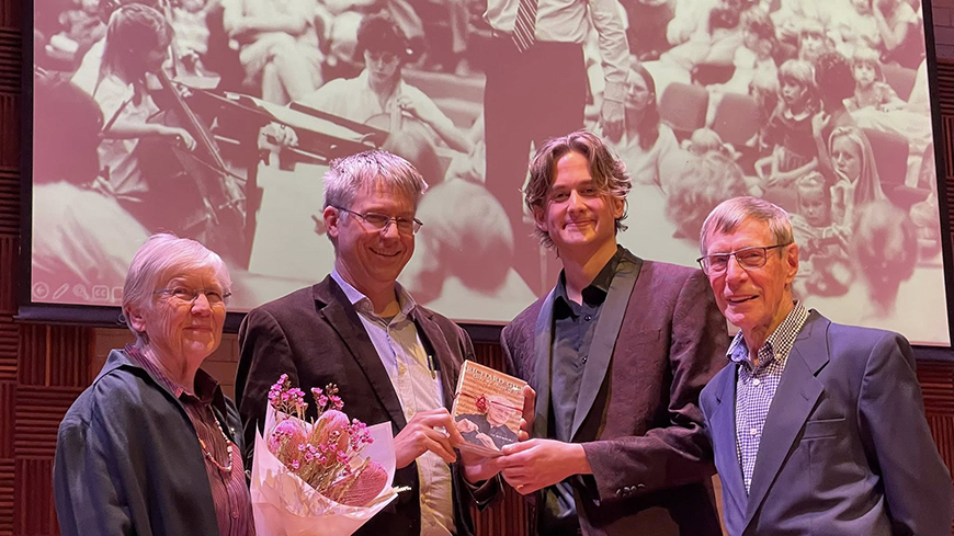 Four people standing in a line with an award