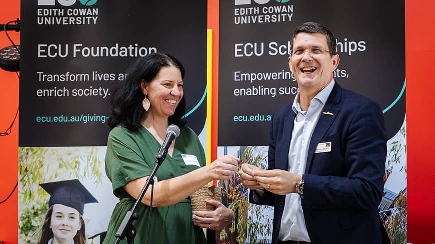 Two people on stage drawing a raffle