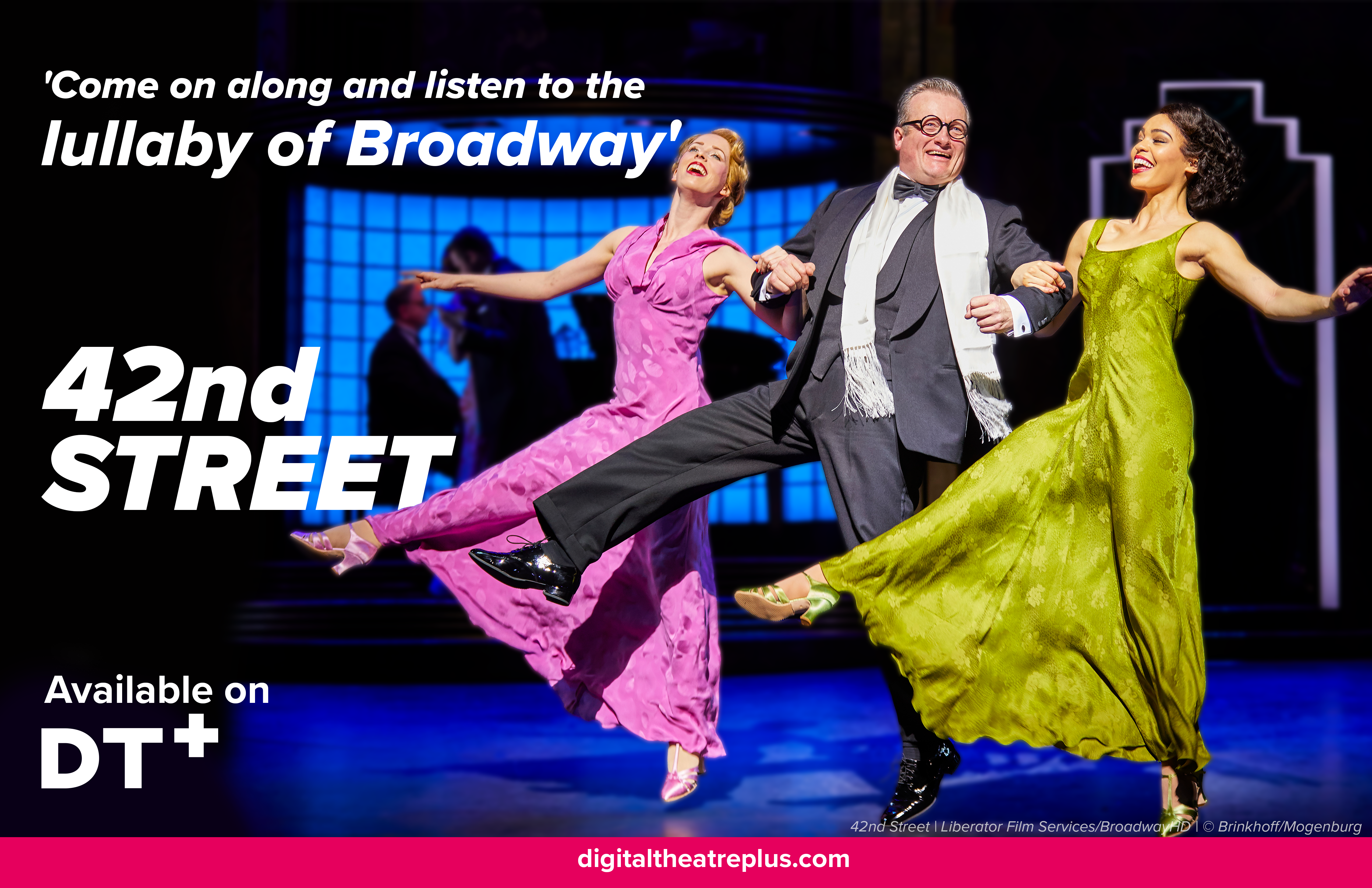 A still shot from a production recording of 42nd street available in Digital Theatre Plus. Three people kick their heels up as they dance across stage. Two wear colourful dresses and one is in a suit, in between them, arms linked.