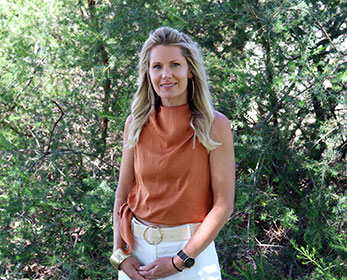 A portrait image of Ms Donna Gallinagh smiling standing in front of a tree.