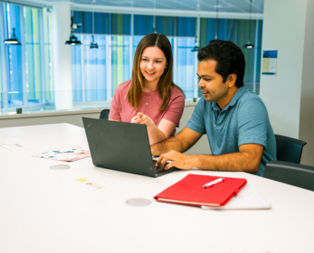 Two students working together on a laptop in a study space, accessing e-textbooks through the updated SAGE Catalyst platform.