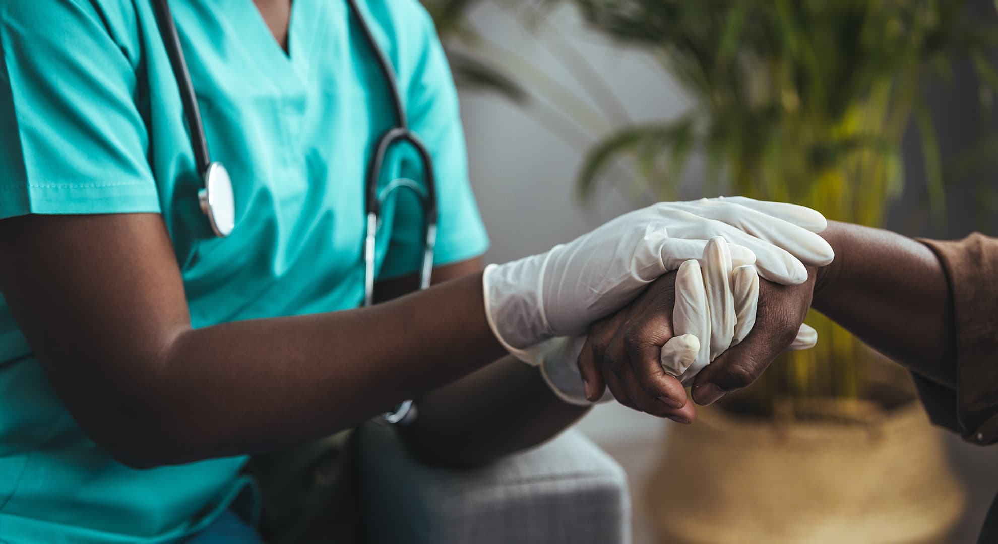 Healthcare worker holding the hands of a patient.