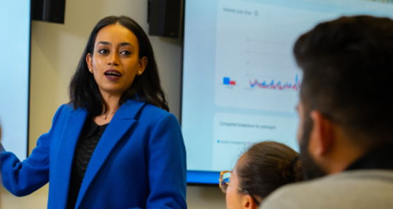 Woman lecturing students by digital whiteboard.