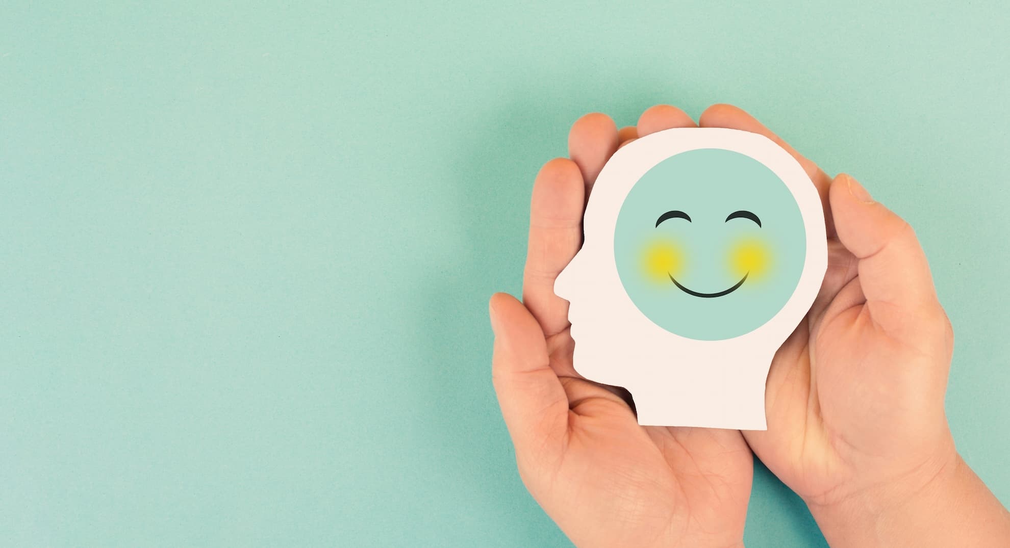 Two hands holding picture of a head with a smiling face.