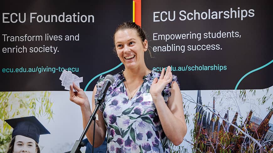 A person on stage smiles while addressing the crowd