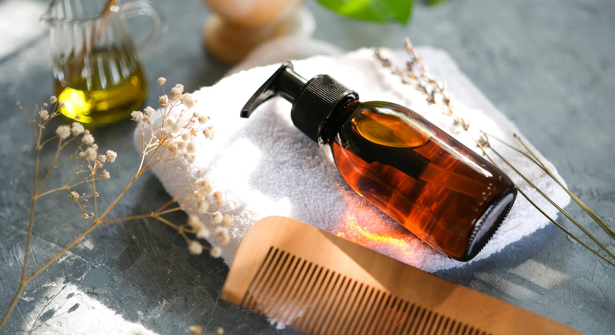A brown bottle of essential oil on a grey background.