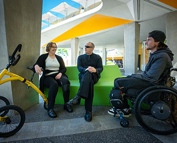 Students sit outside the Joondalup Campus Library socialising. They are in a large spacious area with room for their mobility aids.