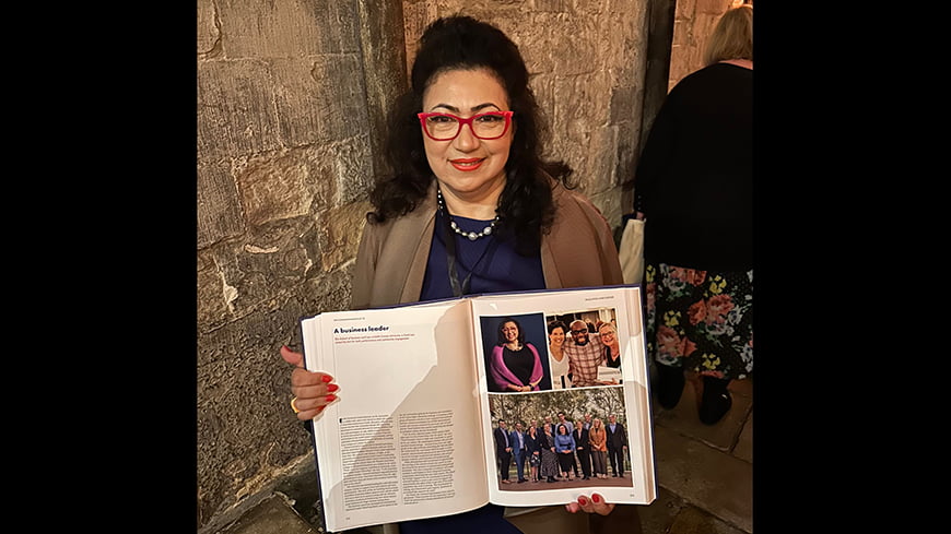 Professor Maryam Omari, holding the commemorative book at Westminster Abbey.