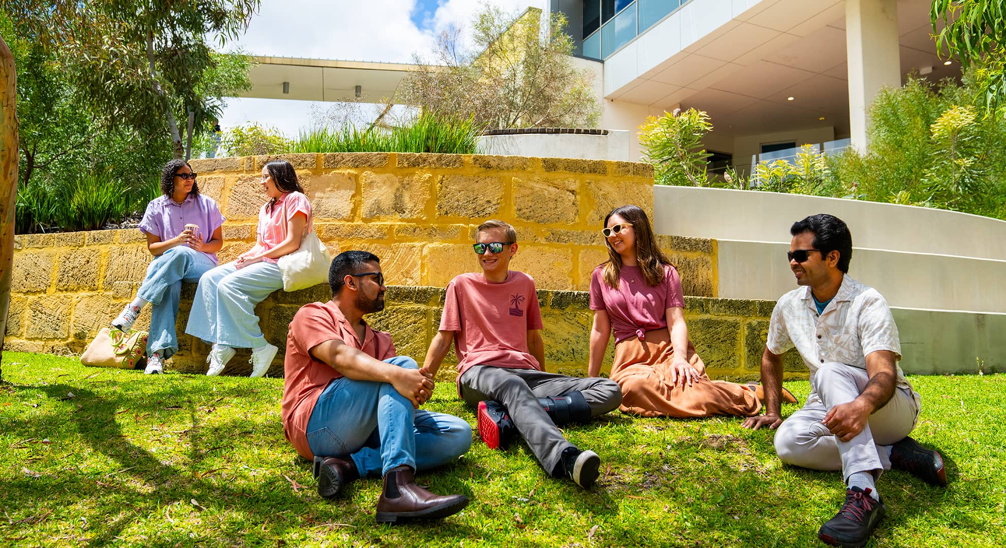 Students laughing and talking on lawn area
