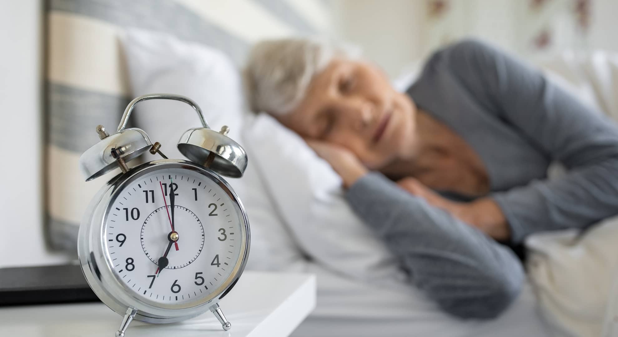 Elderly woman sleeping next to clock