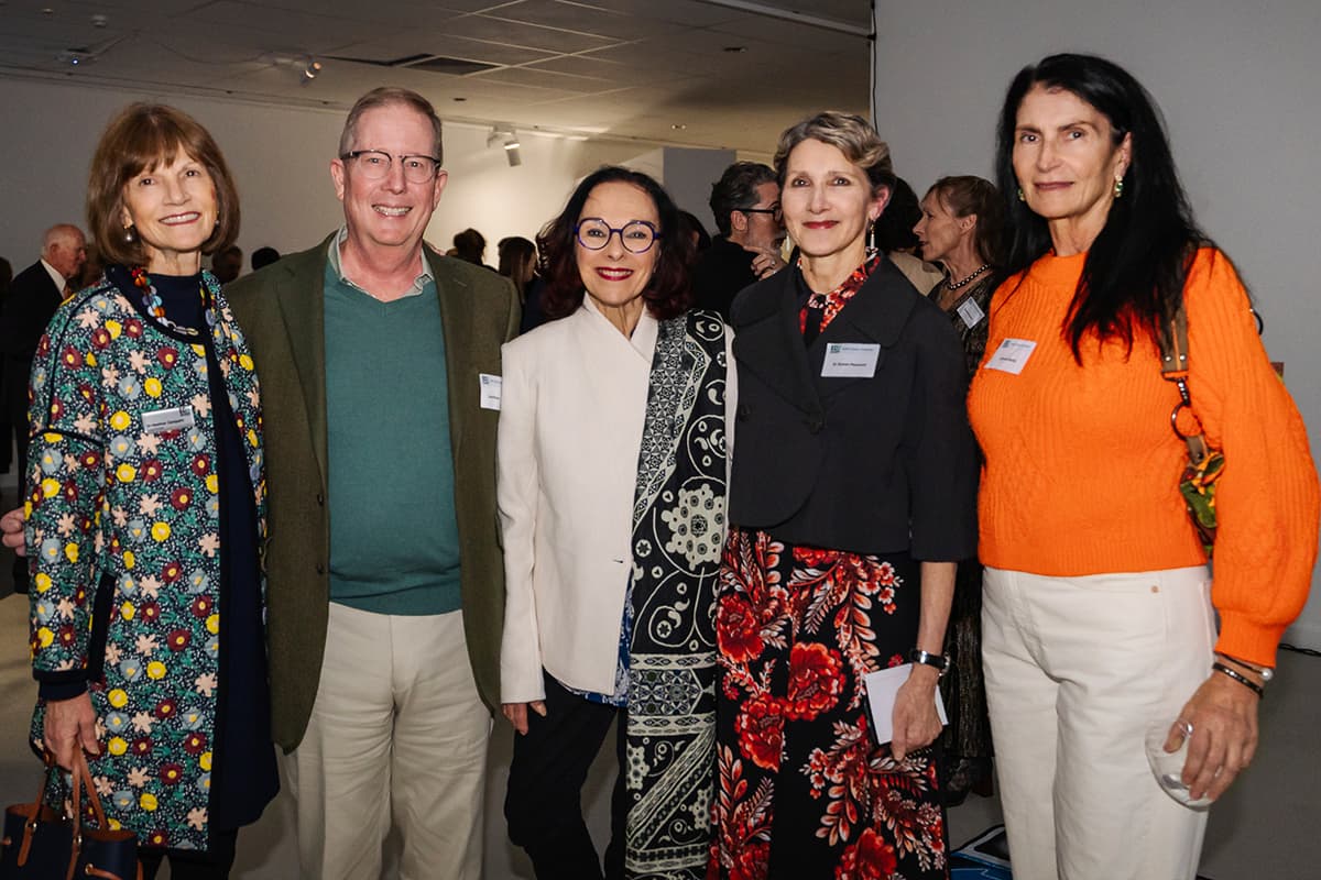 Five people standing in a row - bring orange sweater on right