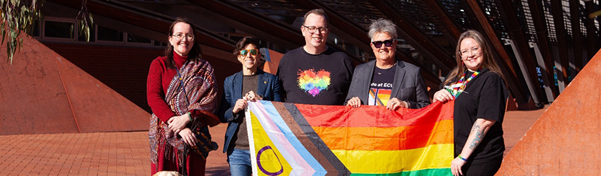group of people standing with a pride flag