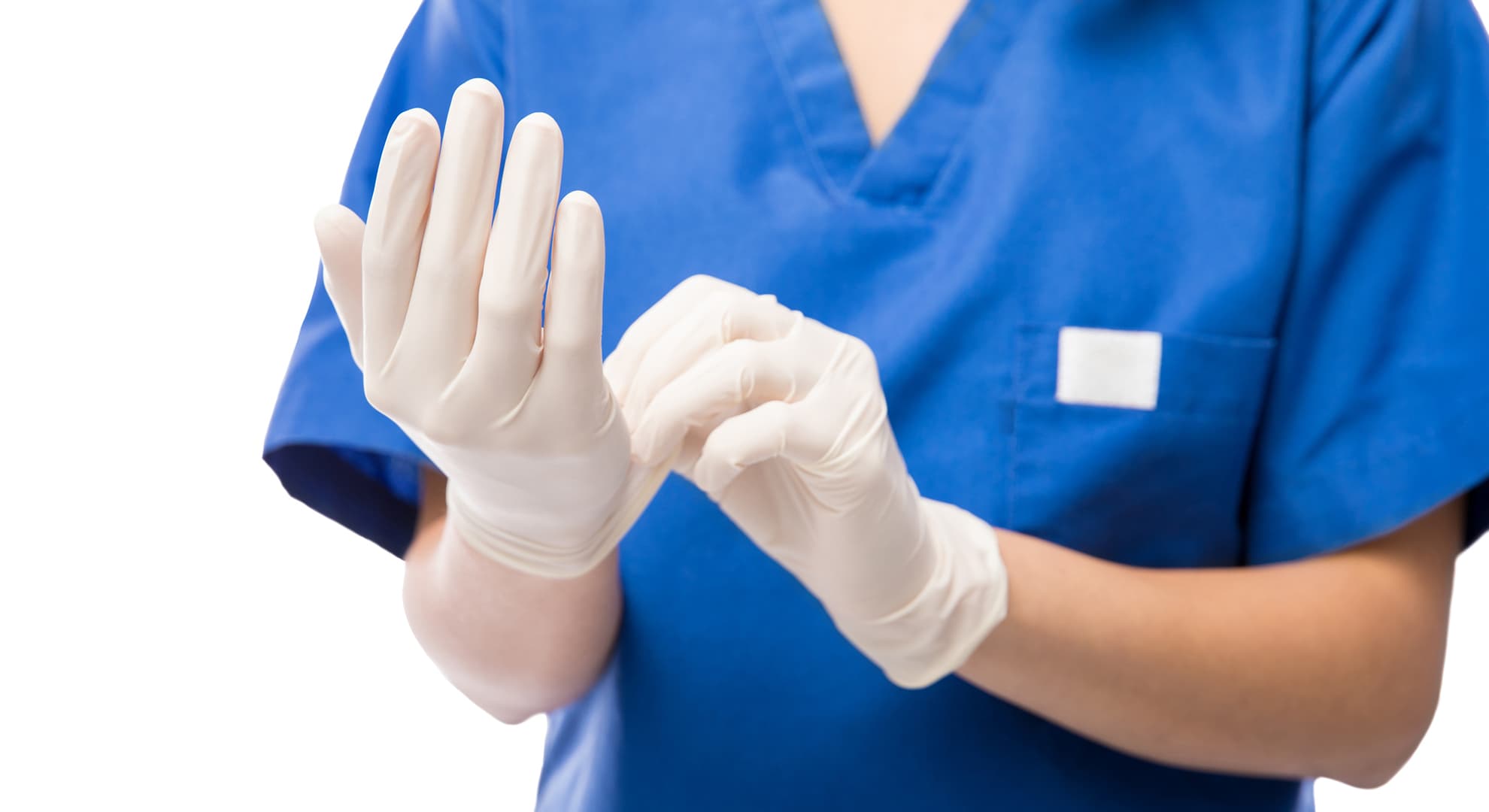 A nurse in blue scrubs putting on white gloves.