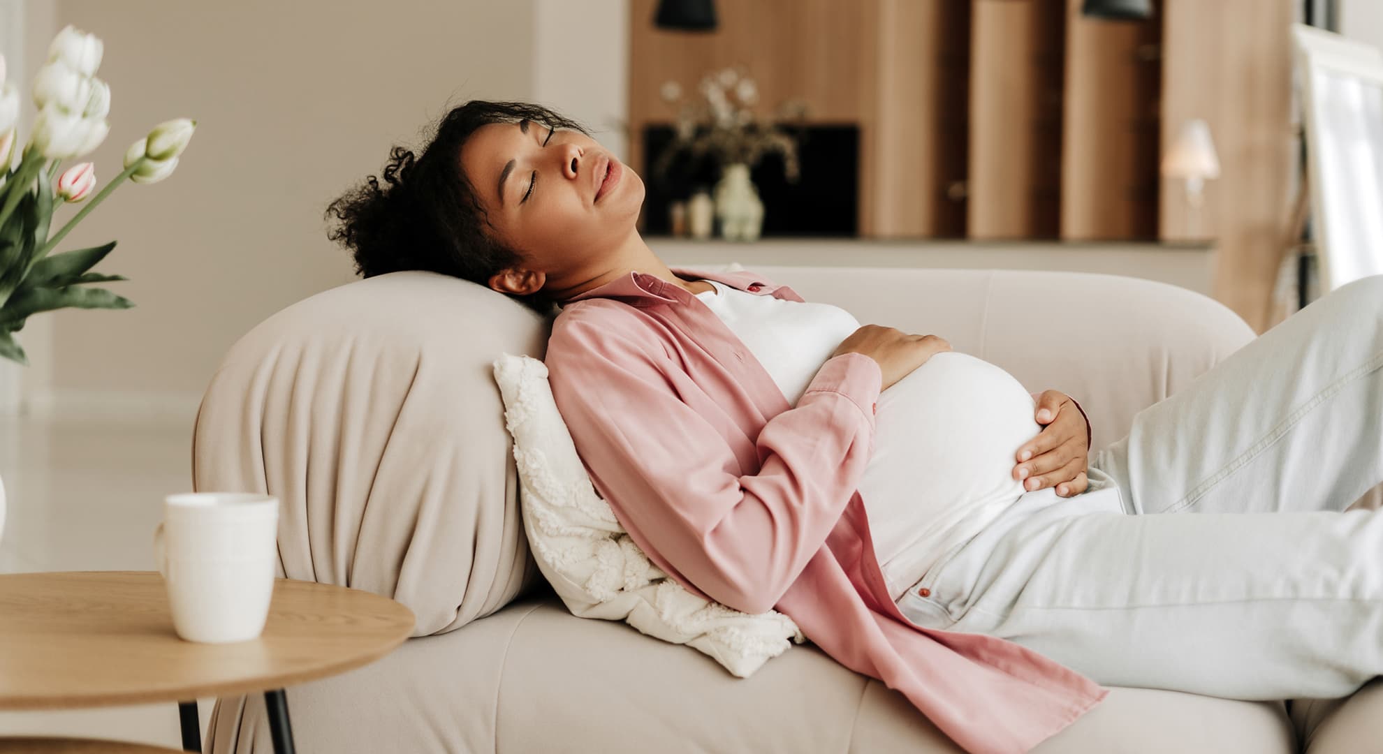 Pregnant woman lying on a couch, holding her stomach.