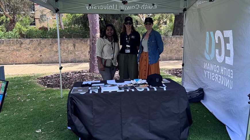 Three people standing under a tent.