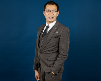 Dr Allen Au in front of a navy blue background