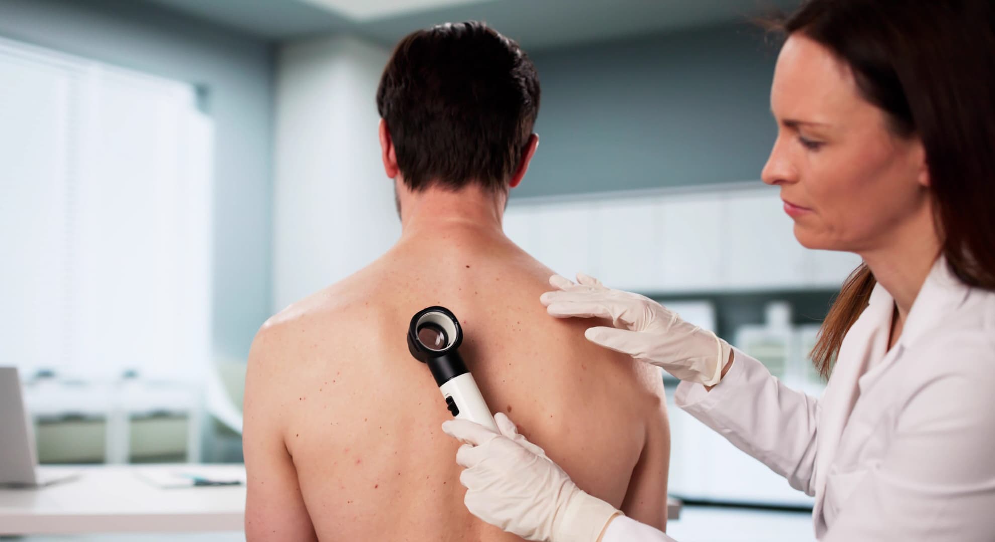 person having skin checked by doctor with a magnifying glass