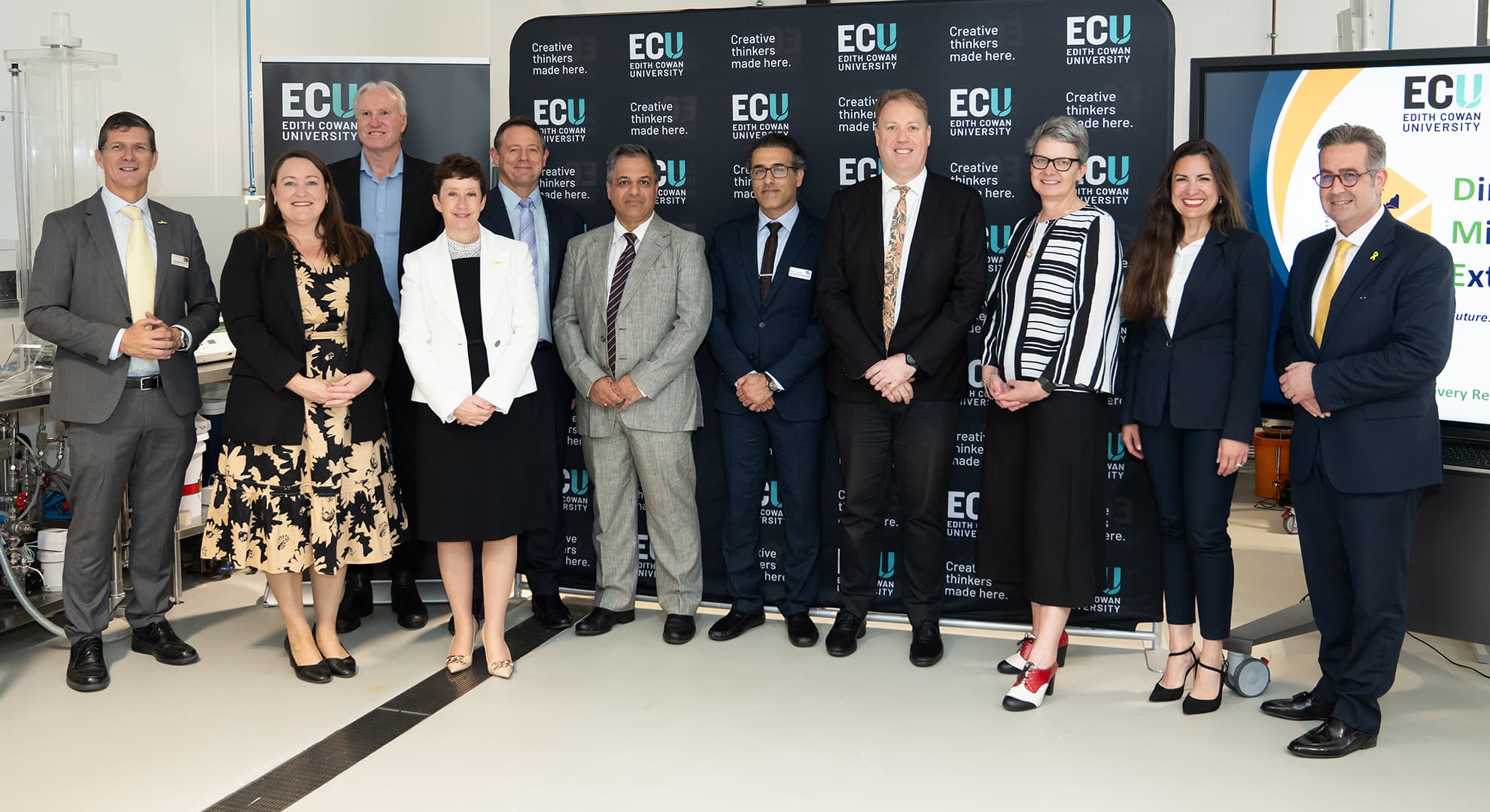 Eleven people standing in front of an ECU banner.