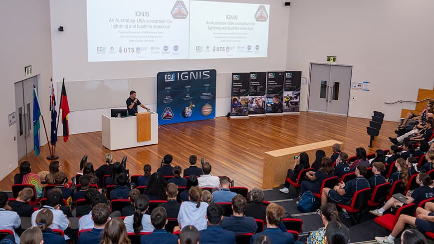 Prof De Souza presenting in front of white board.