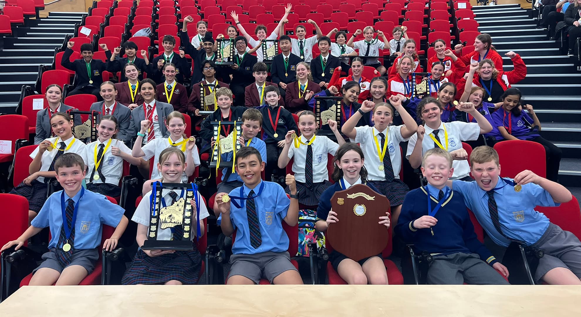 Children sitting with trophies celebrating.