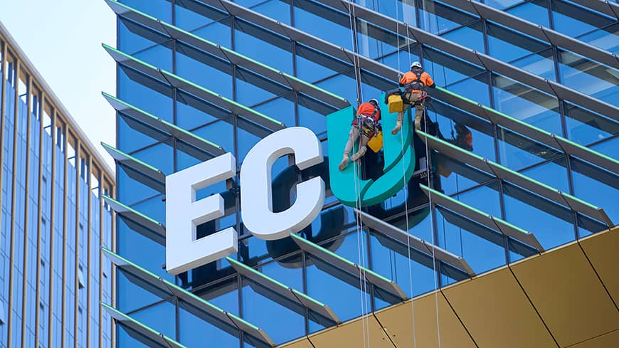 Men hanging from a building putting up a sign