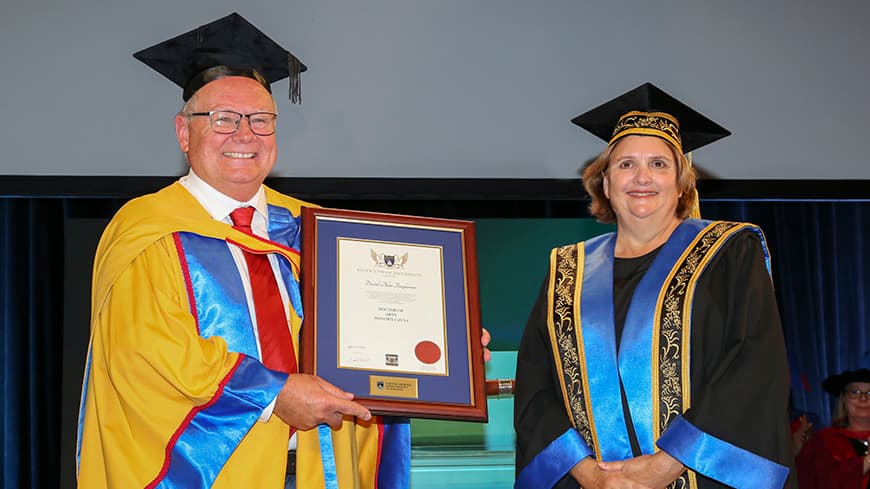 A man, Dave Templeman, receiving an award from a woman, ECU Chancellor Gaye McMath