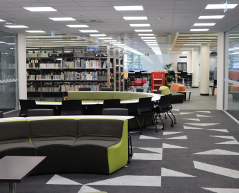 Joondalup Campus Library Level 3 study area with bookshelves, seating, and bright overhead lighting.