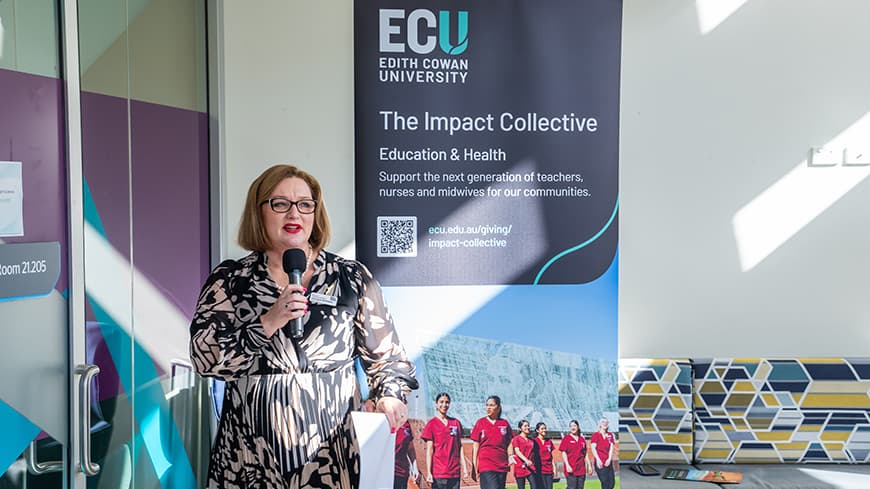 Woman standing in front of banner with a microphone.