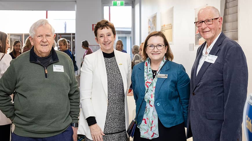 Four people standing in a row facing the camera