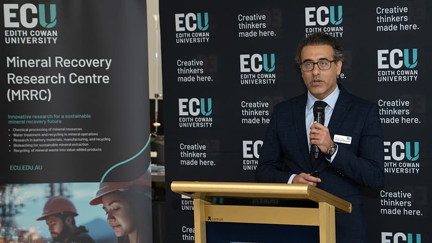 A man in front of a podium with ECU signage.
