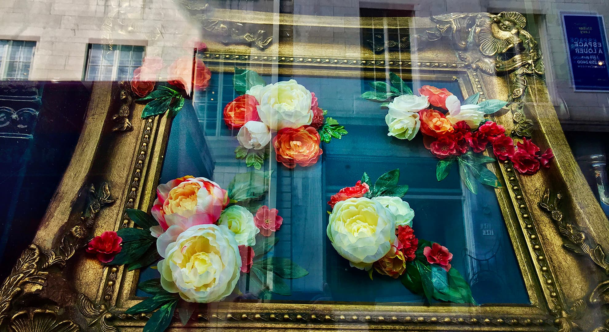 A framed painting photographed through a storefront window.