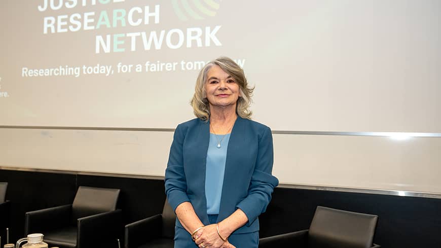 A mid range shot of a woman facing the camera in front of a large screen