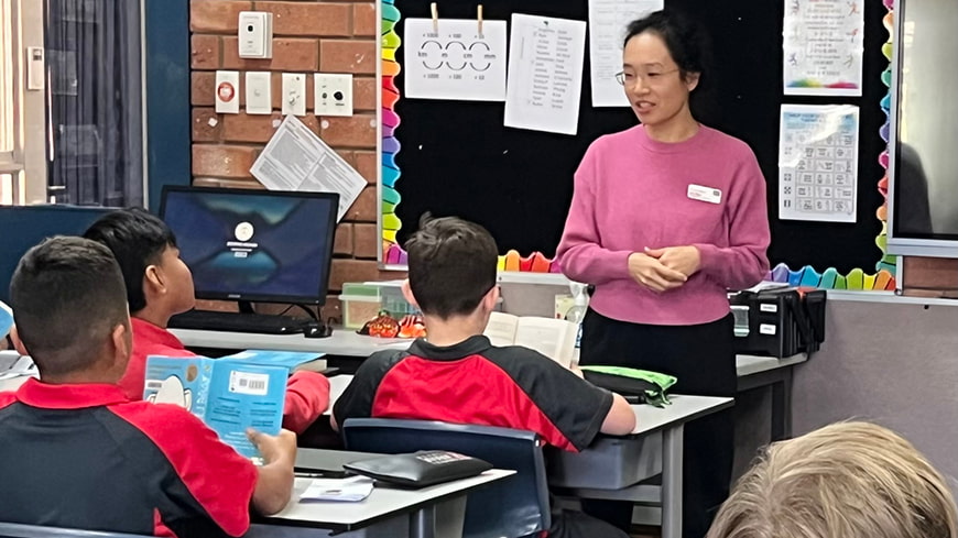 Wendy Fan wears a pink sweater in the classroom teaching primary school students.