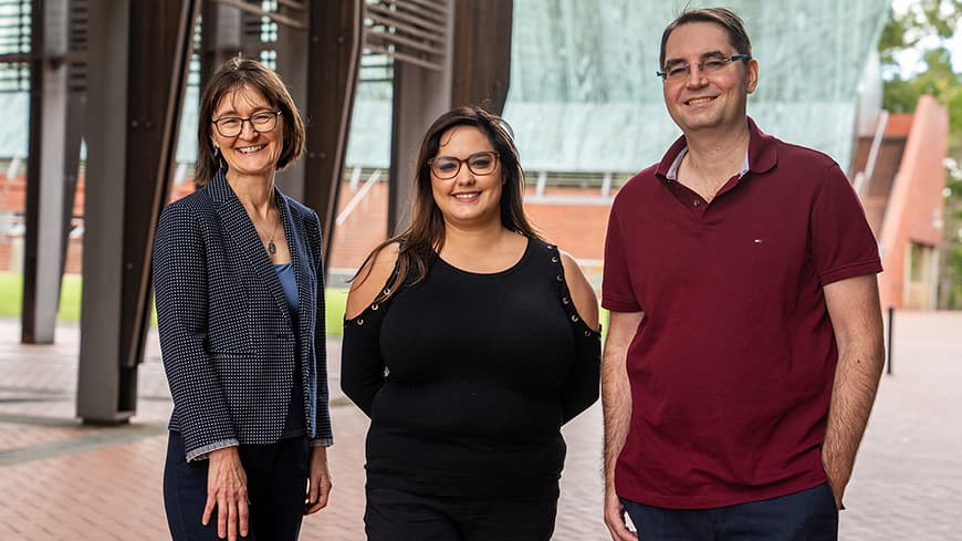 Three people standing in a row outside in the undercroft of ECU Joondalup's main building 1