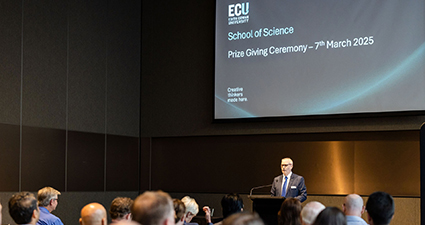 A man on stage speaking to a crowd