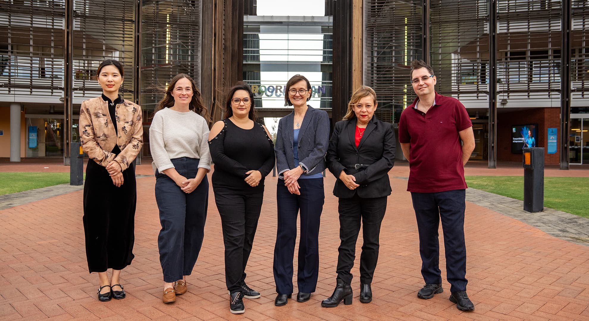 Six people standing in a row outside in front of ECU Joondalup's main building 1