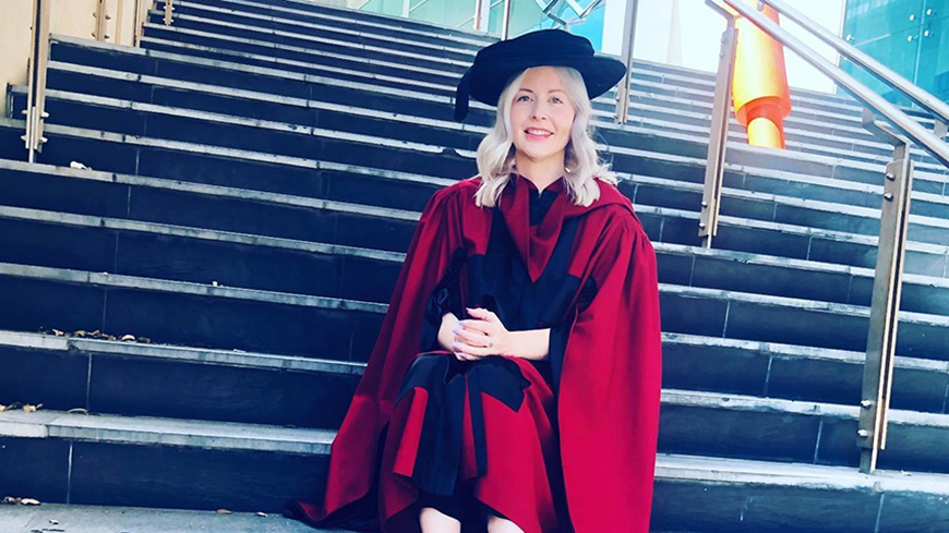 woman sitting on steps in academic regalia