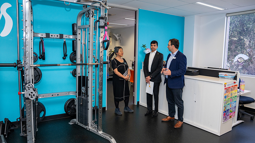 Two men and a woman standing in a gym.