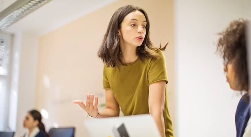 Two women having a discussion in front of a computer screen