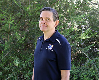 A portrait of Mr Marco Tolomei standing in front of trees