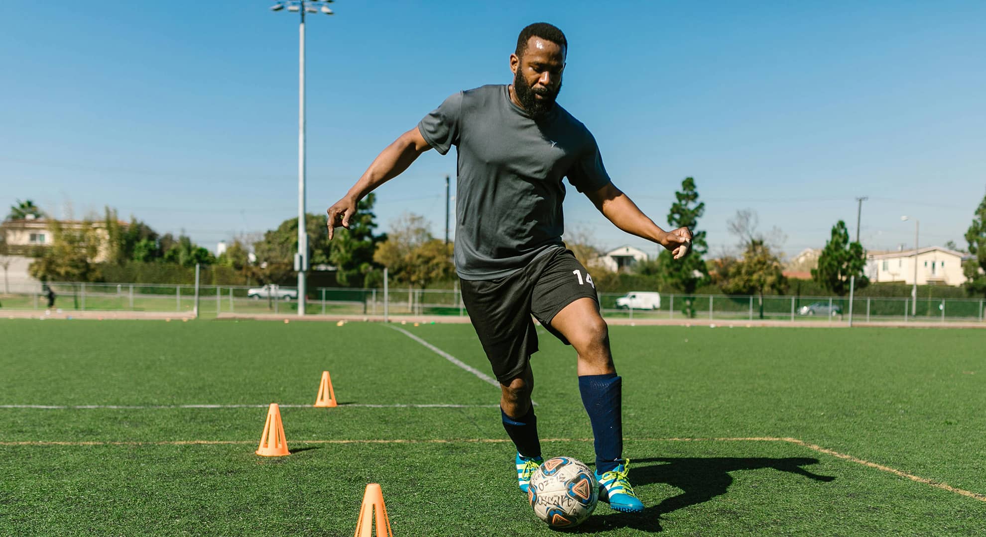 Man dribbling a soccer ball on a sports pitch.