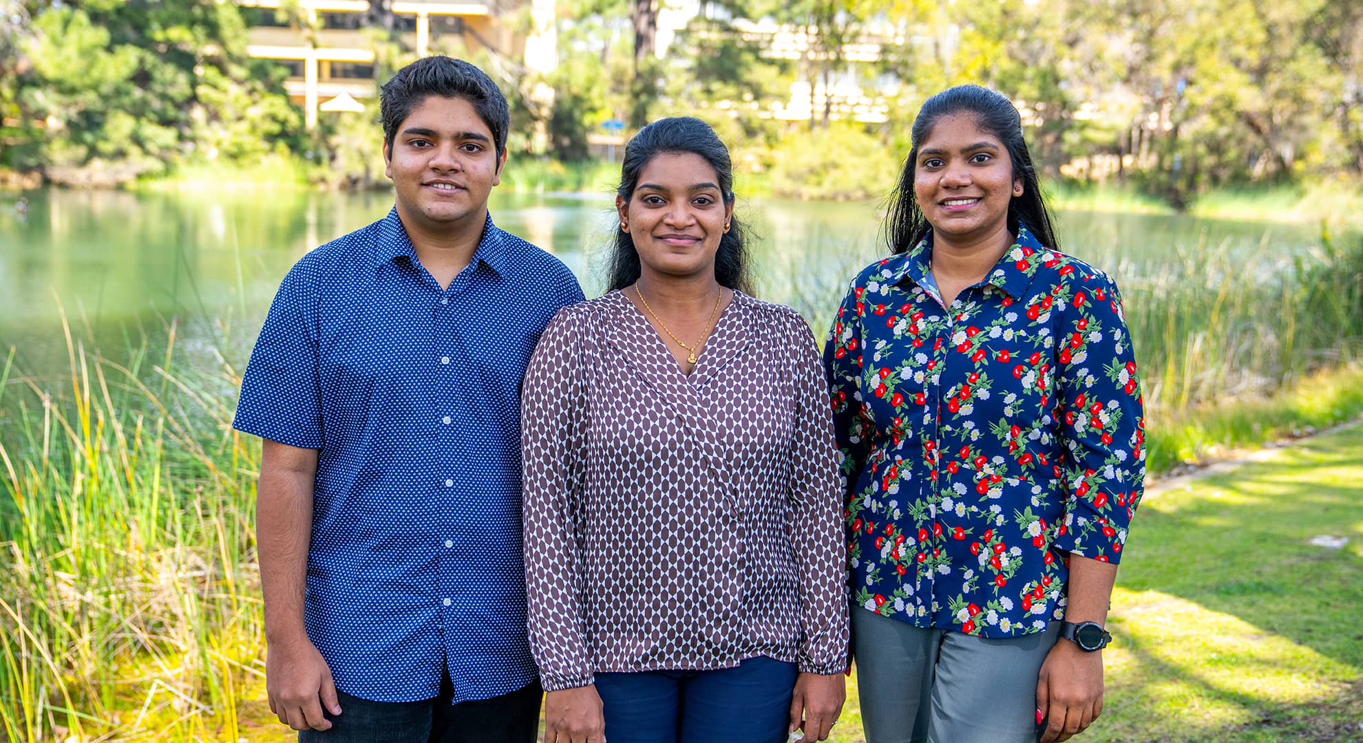 Two women and a man standing by a lake