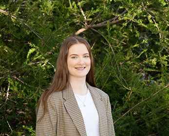 A portrait of Mrs Taylah Grey standing in front of a tree.