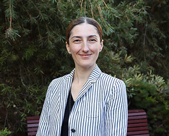 Dr Serap Sevimli-Celik smiling and standing in front of a tree