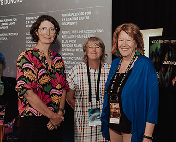 3 female ECU staff members standing in front of the AIDC banner.