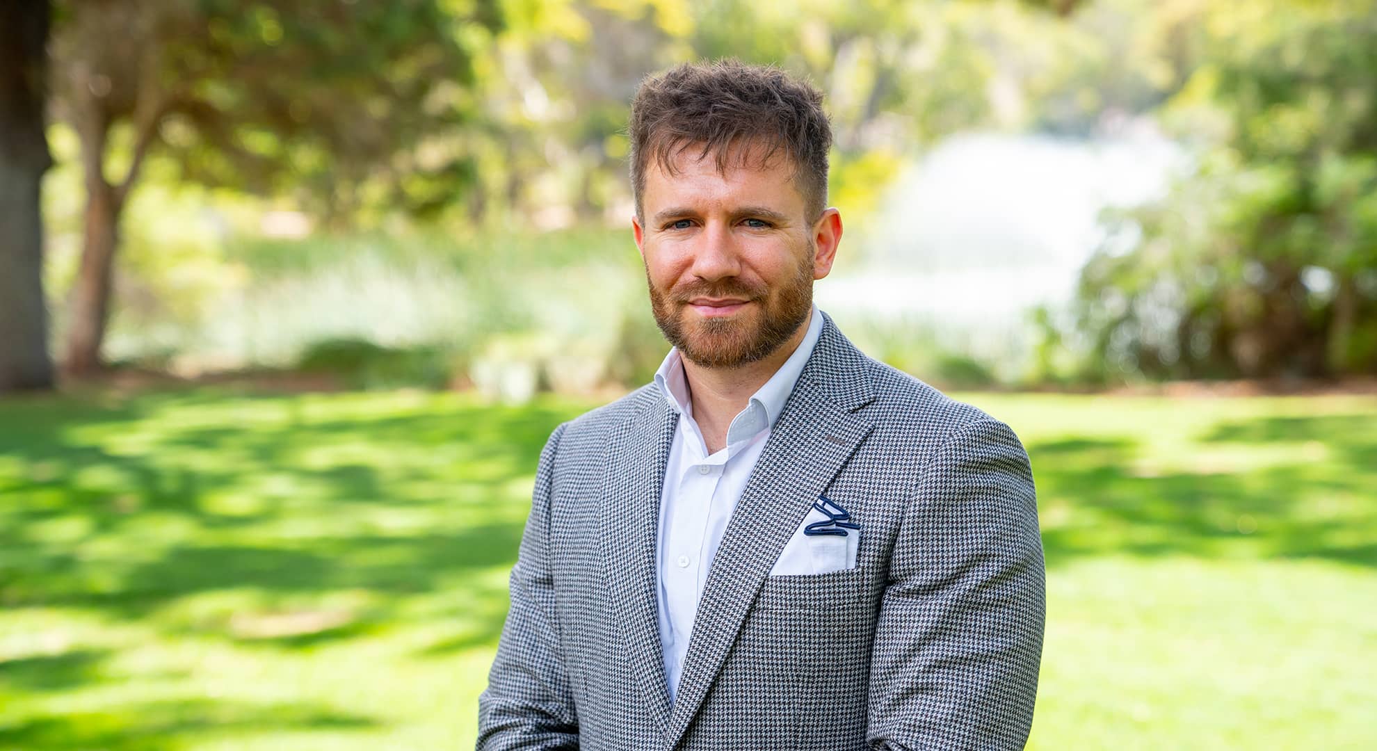 A man standing in front of a natural green background