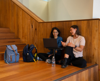 Two students sit on wooden steps in the ECU Library, using a laptop to explore Beama Film’s collection of award-winning films and documentaries.