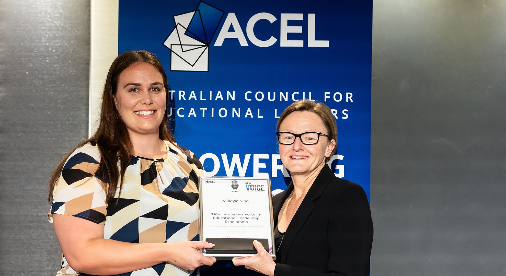 Two women standing with an award.