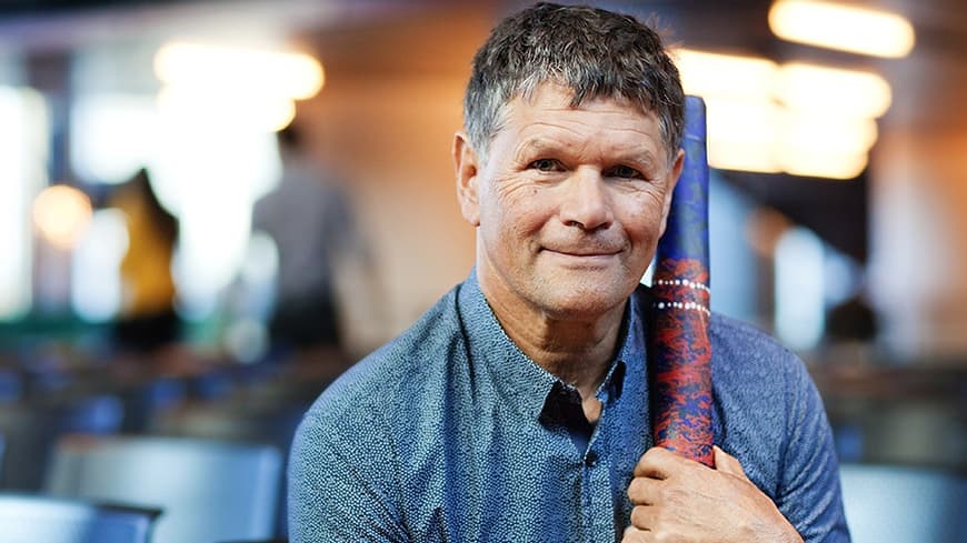 man smiling with a didgeridoo.